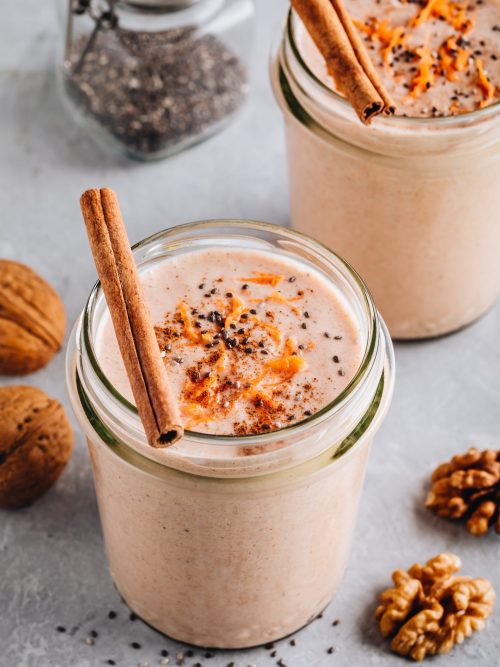 Two Low FODMAP Carrot Cake smoothies in glass jars with orange and white straws.