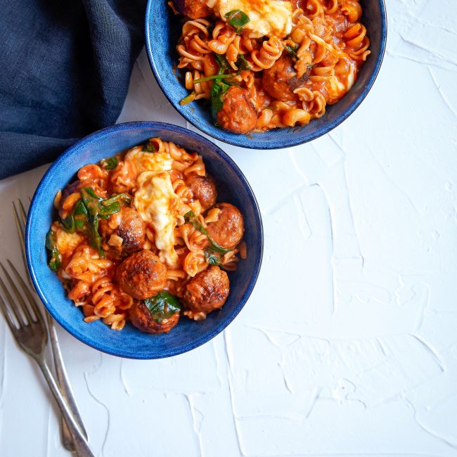One-pot-penne-meatball-served-in-two-blue-bowls-on-a-white-background.