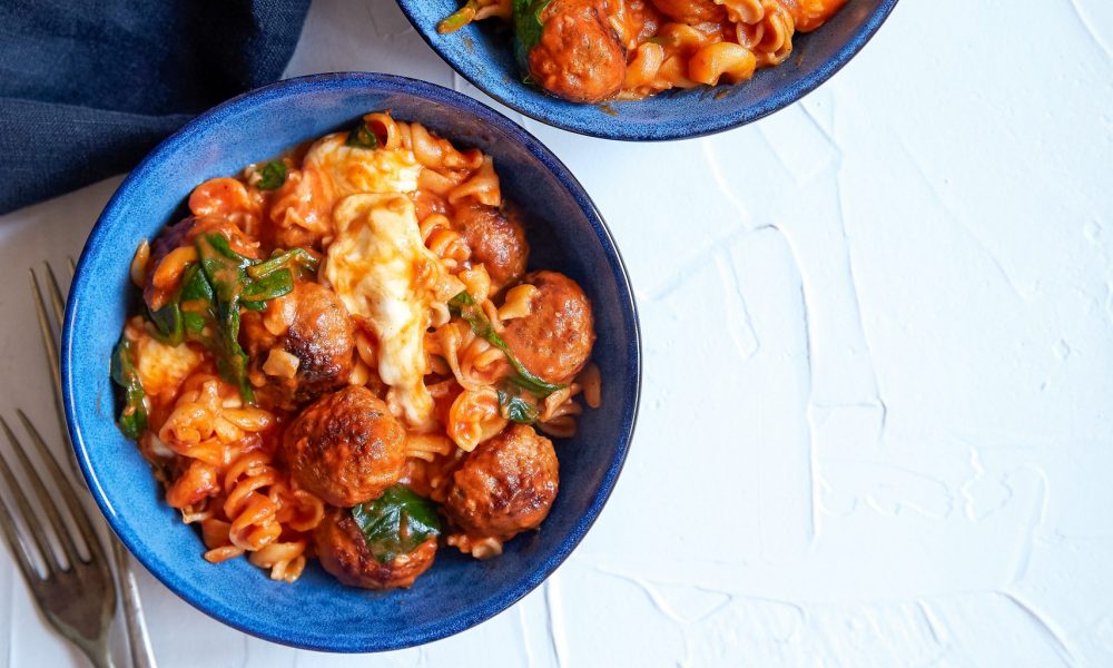 One-pot-penne-meatball-served-in-two-blue-bowls-on-a-white-background.
